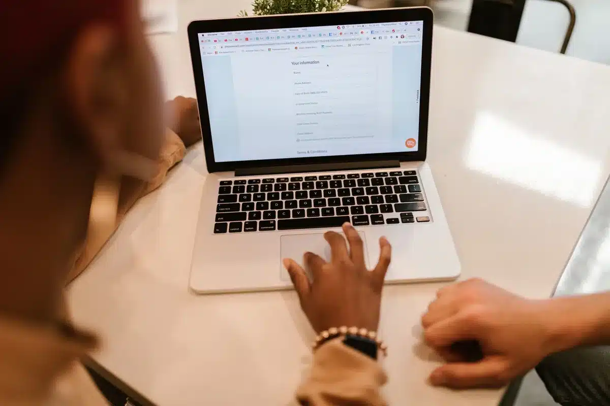 Étudiant remplissant un formulaire de demande d'aide en ligne sur son ordinateur