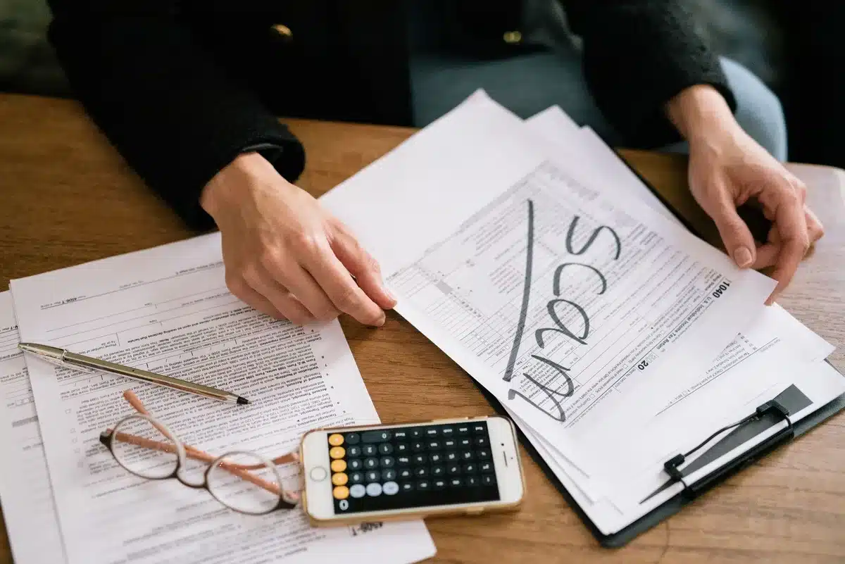 Personne examinant des documents financiers et des relevés bancaires sur un bureau