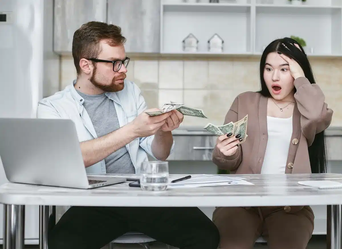 Deux personnes discutant autour d'un document financier avec des billets et une calculatrice