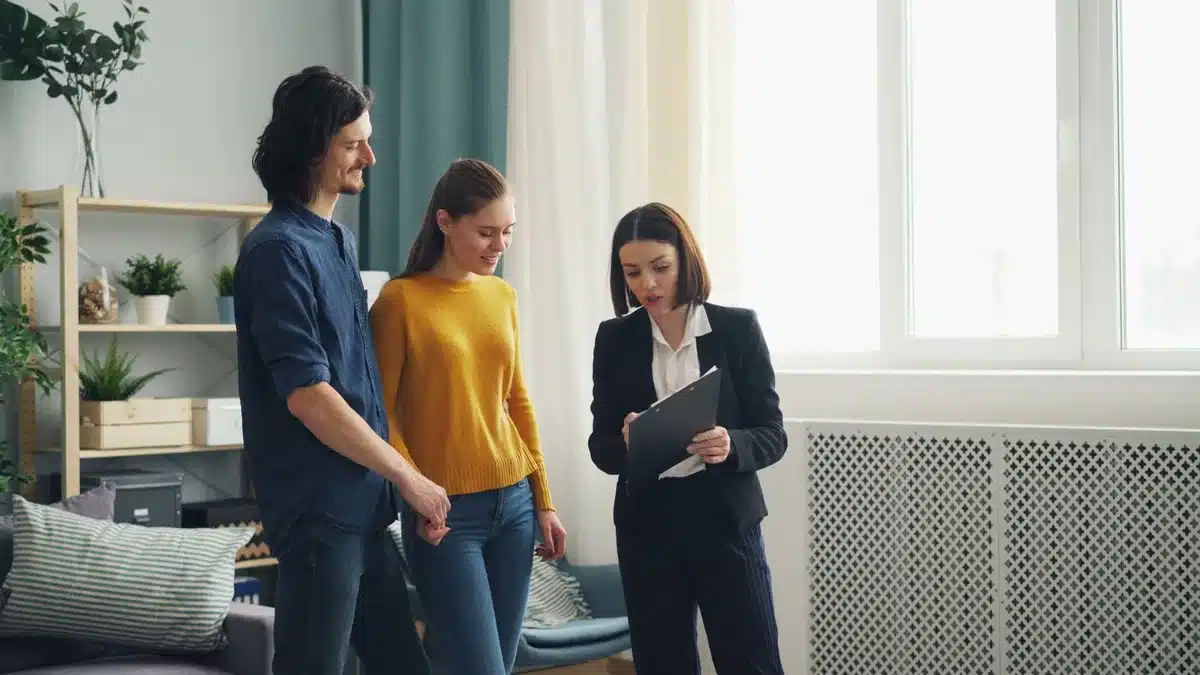 Gros plan sur une main tendant une enveloppe d'argent avec des documents immobiliers et une maquette de maison en arrièr