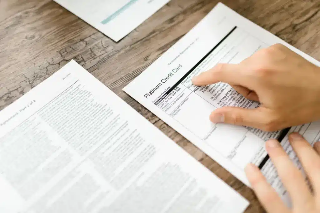 Personne examinant des documents contractuels et de la correspondance sur un bureau pour comparer les offres