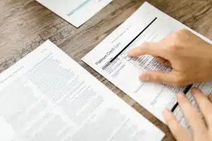 Personne examinant des documents contractuels et de la correspondance sur un bureau pour comparer les offres
