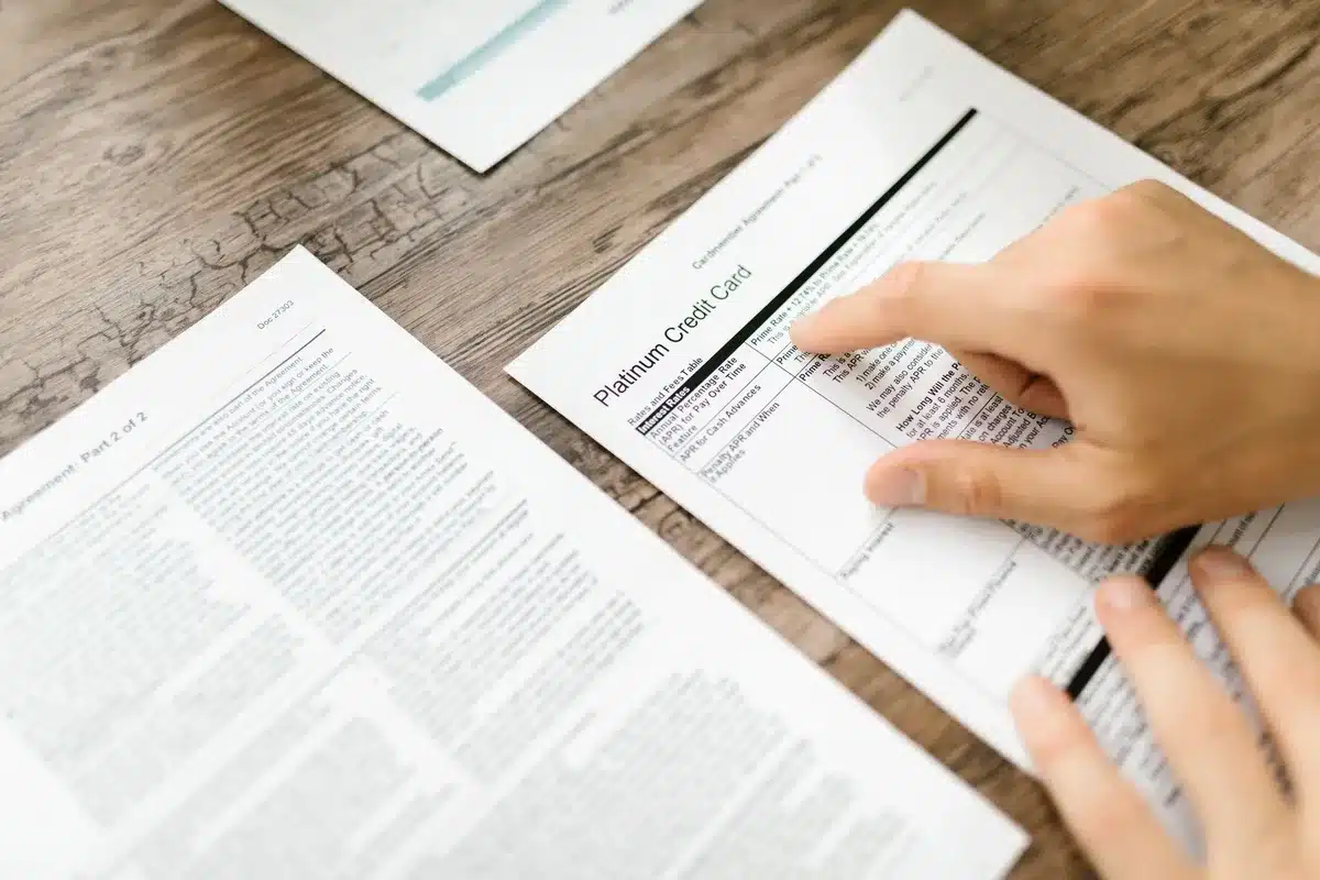 Personne examinant des documents contractuels et de la correspondance sur un bureau pour comparer les offres