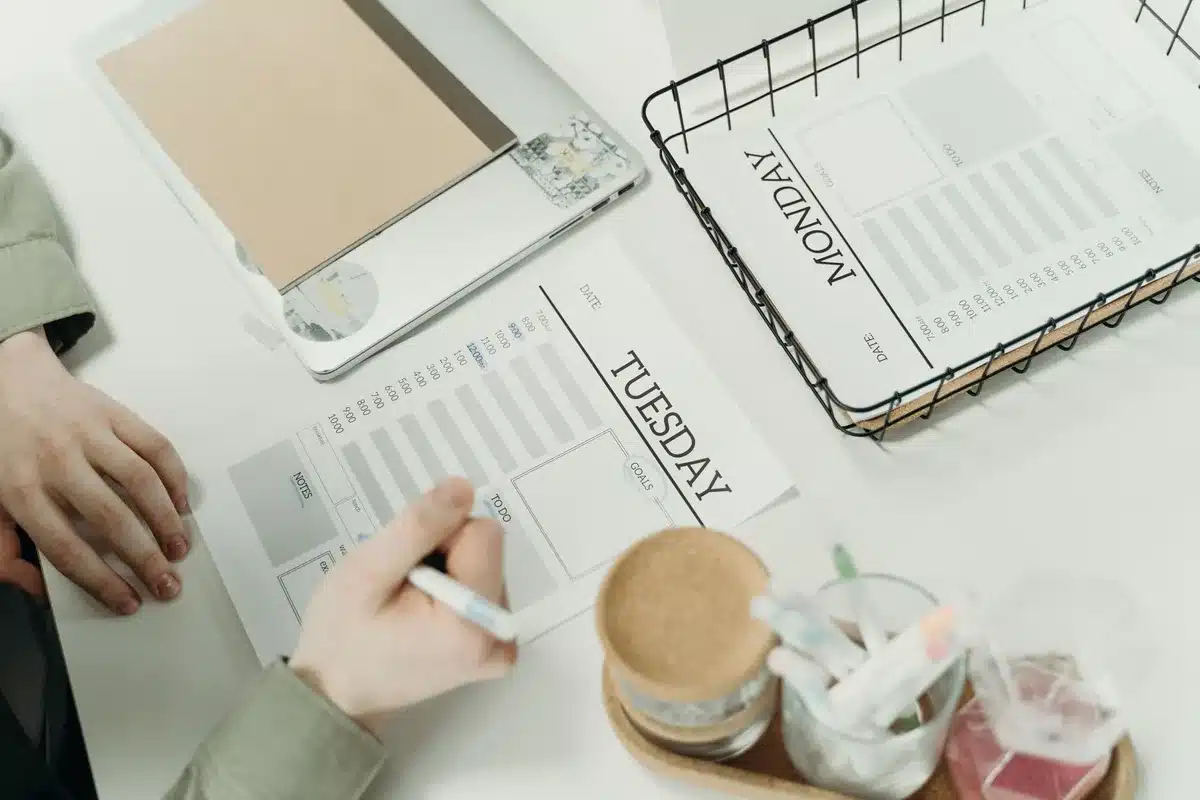Bureau d'entrepreneur avec cahiers, graphiques et ordinateur affichant des plans et feuilles de calcul