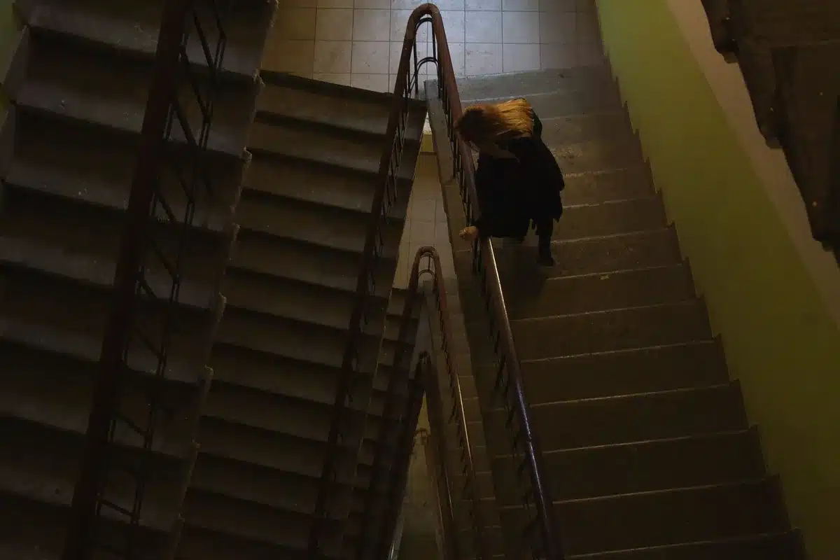 Escalier d'immeuble avec valises de touristes et résidents passant devant