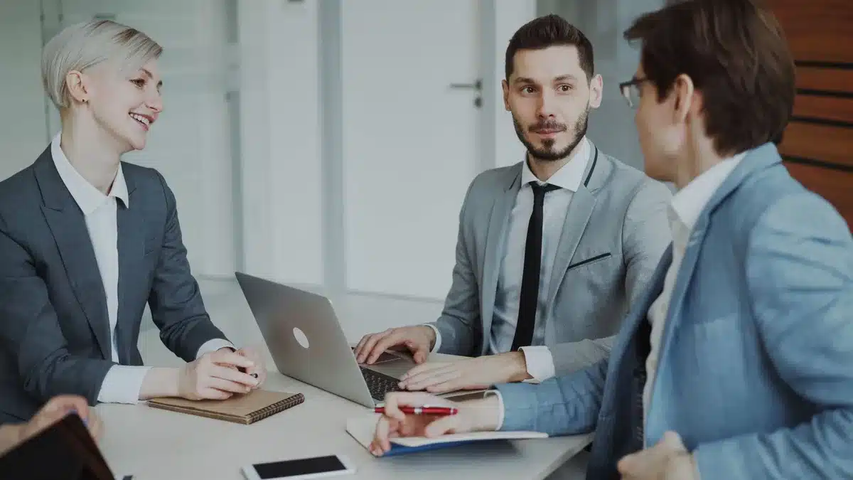 Réunion d'équipe autour d'une table avec participants concentrés et documents partagés