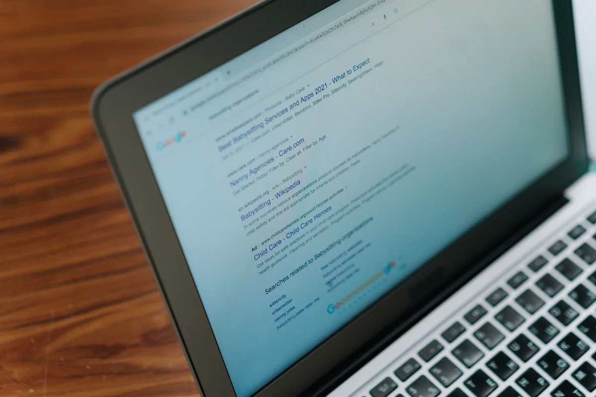 Utilisateur tapant une requête de recherche sur un clavier d'ordinateur portable avec suggestions affichées