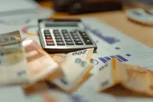 Main de salarié tenant des documents de paie et d'épargne à côté d'un ordinateur affichant des graphiques de croissance
