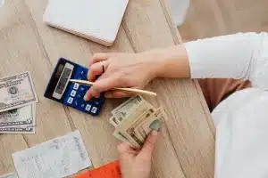 Personne calculant son budget mensuel face à des factures et relevés bancaires