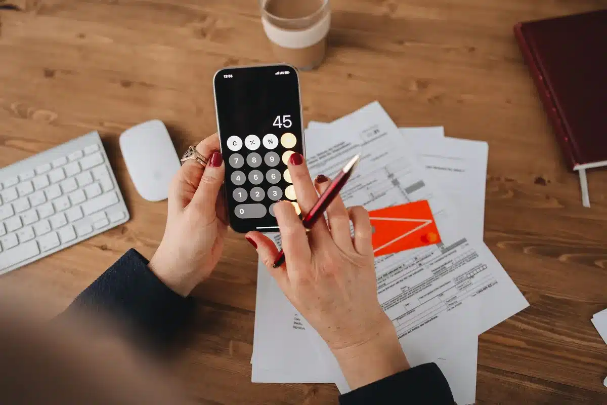 Mains anonymes triant des documents fiscaux et historiques de transactions cryptographiques sur un bureau avec calculatr