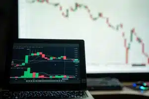 Mains tapant sur un clavier d'ordinateur portable avec code API et interface de trading en arrière-plan