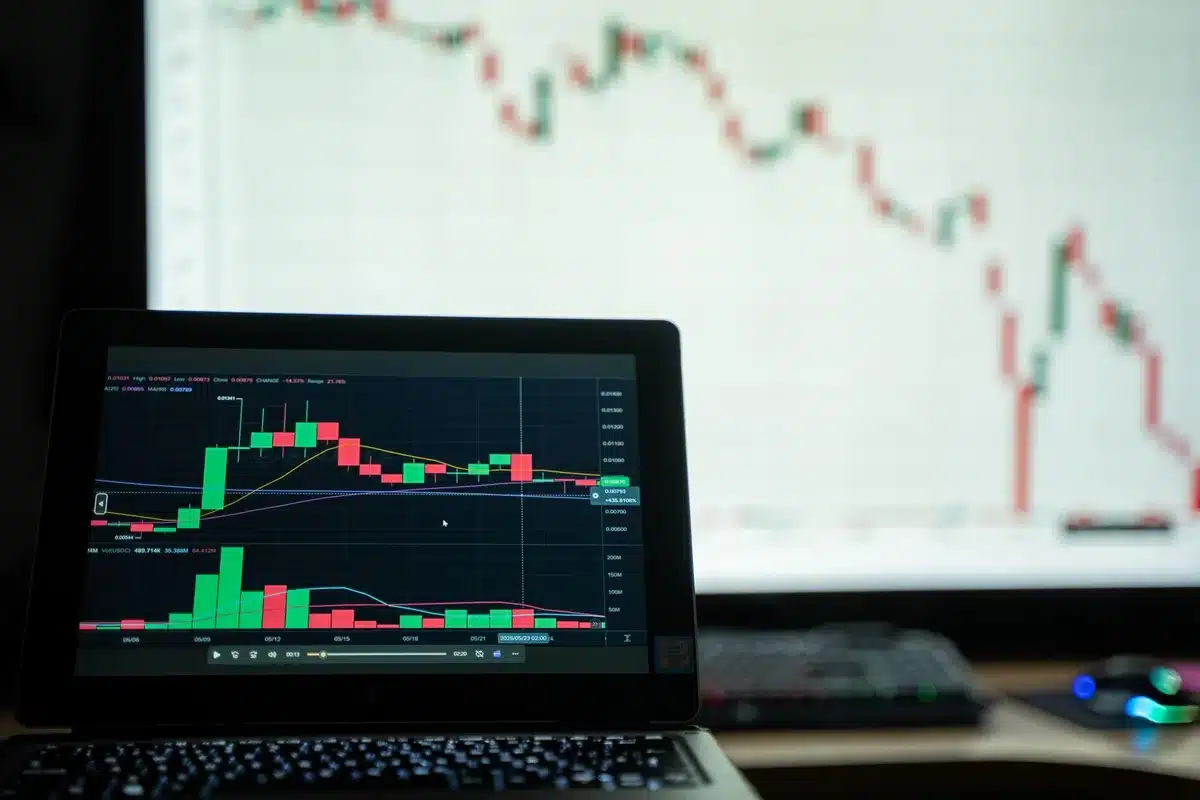 Mains tapant sur un clavier d'ordinateur portable avec code API et interface de trading en arrière-plan