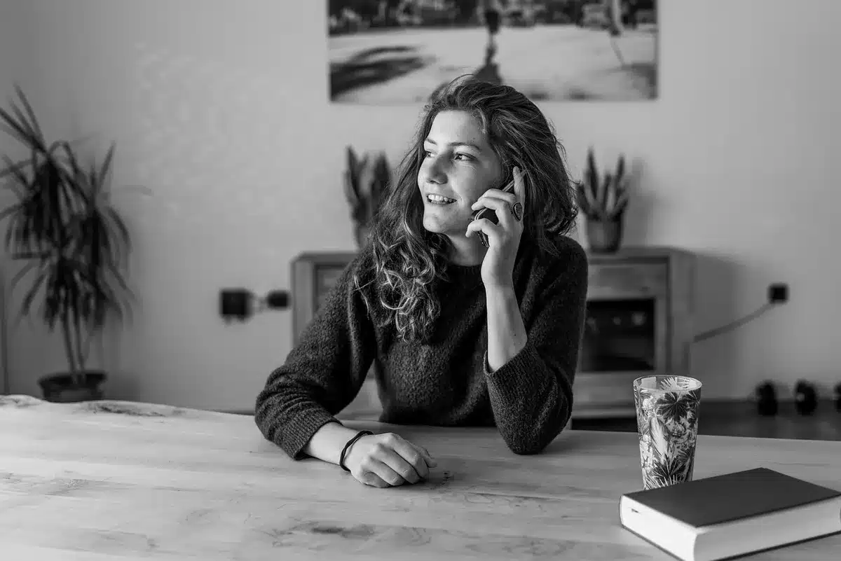 Mains tenant des pièces et un téléphone affichant des graphiques financiers