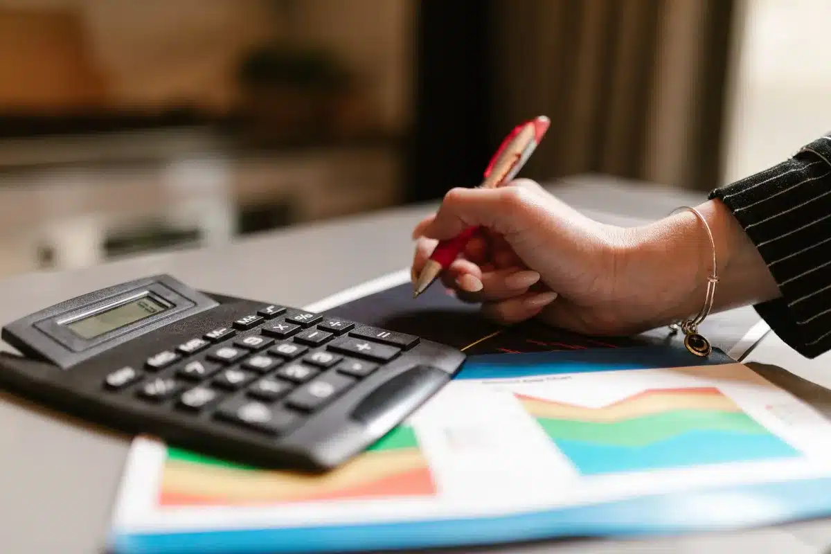 Mains triant des documents financiers et prospectus de fonds sur un bureau avec calculatrice