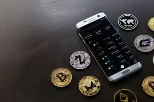 Main d'une personne utilisant une application bancaire mobile affichant des données de crypto-monnaies