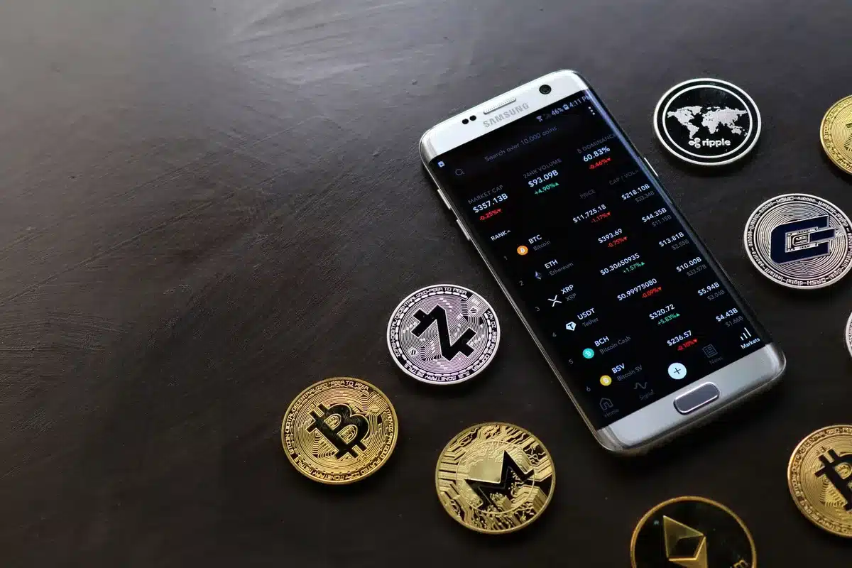 Main d'une personne utilisant une application bancaire mobile affichant des données de crypto-monnaies