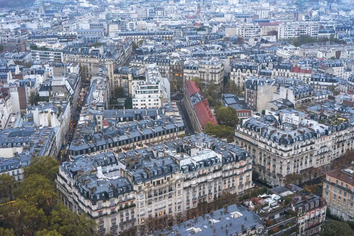 Un appartement parisien ancien vide avec fenêtres hautes et murs clairs, symbolisant l'hésitation face à l'achat immobil