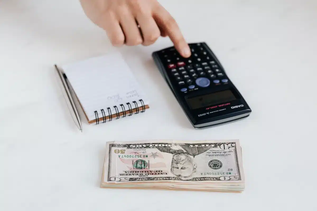 Documents financiers, calculatrice et stylo sur un bureau avec une main qui les examine