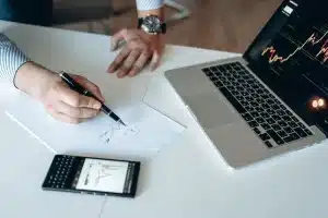 Mains d'une personne devant un écran d'ordinateur affichant des graphiques de trading et des symboles crypto