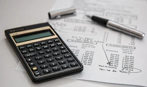 Bureau avec formulaires fiscaux, documents budgétaires et calculatrice en désordre