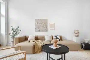 Appartement en plein jour avec fenêtre, volets partiellement fermés et ventilateur sur une table