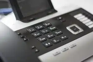Personne écoutant attentivement lors d'un appel vidéo professionnel, bloc-notes à proximité