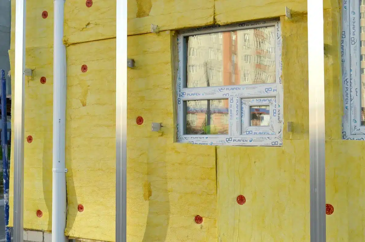 Travailleur posant de l'isolation dans des combles lors d'une rénovation énergétique