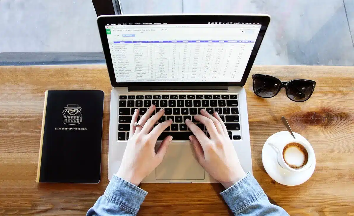 Bureau lumineux avec carnet montrant une matrice à quatre cases et mains collant des post‑it