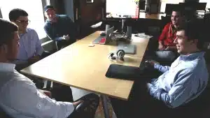 Équipe B2B anonyme en réunion autour d'ordinateurs et tableau blanc