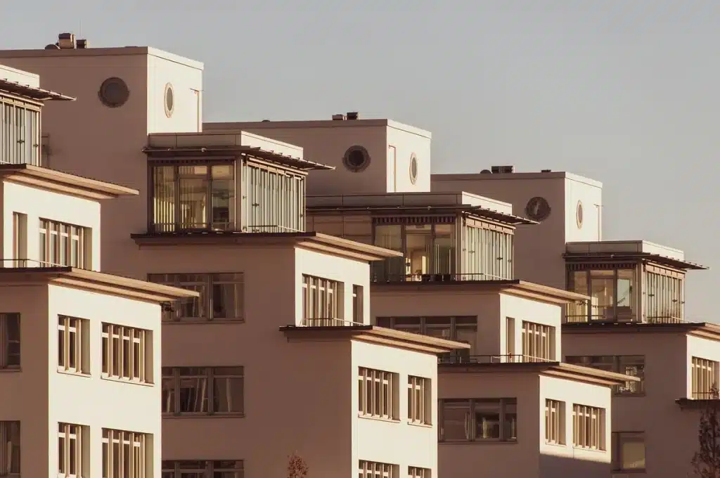 Main d'une personne tenant un stylo au-dessus de documents immobiliers et d'une calculatrice
