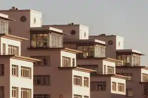Main d'une personne tenant un stylo au-dessus de documents immobiliers et d'une calculatrice