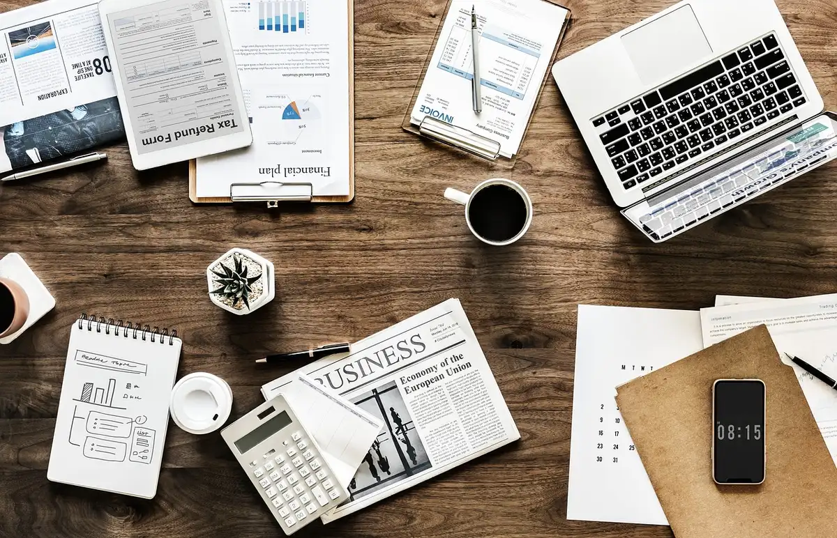 Mains esquissant un plan commercial sur papier avec documents et outils de planification sur un bureau