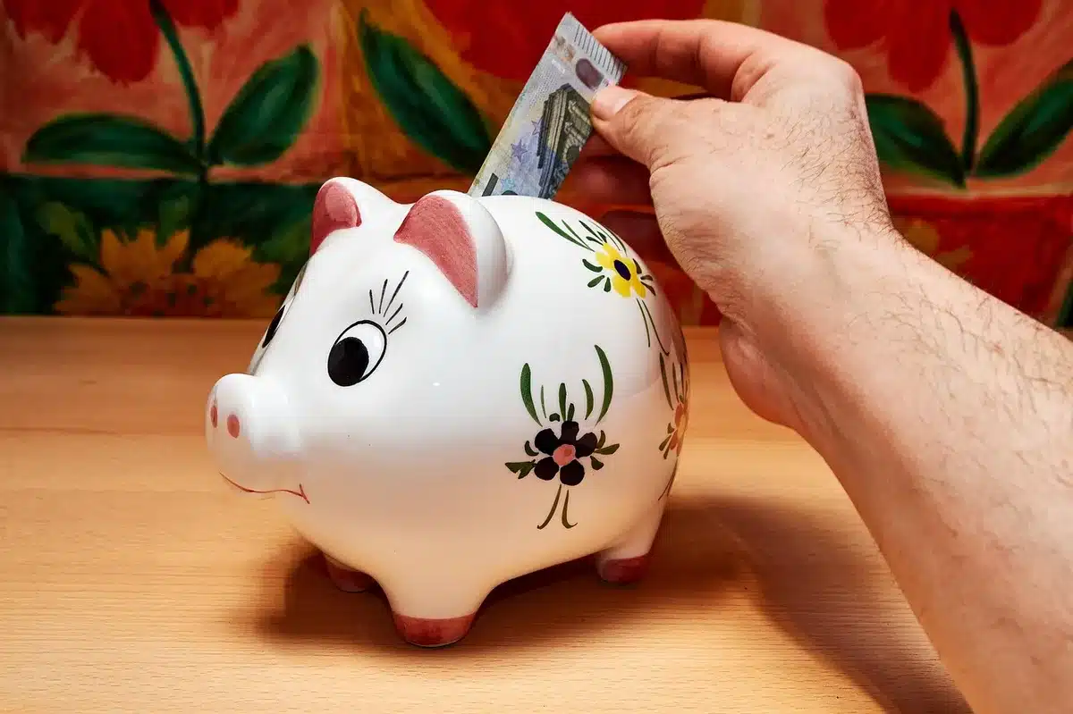 Main tenant un contrat d'assurance‑vie et une calculatrice près d'une fenêtre en jour