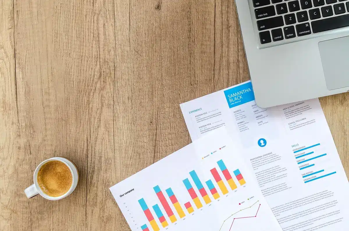 Bureau en journée avec documents d'investissement, ordinateur et mains sur une fiche de fonds