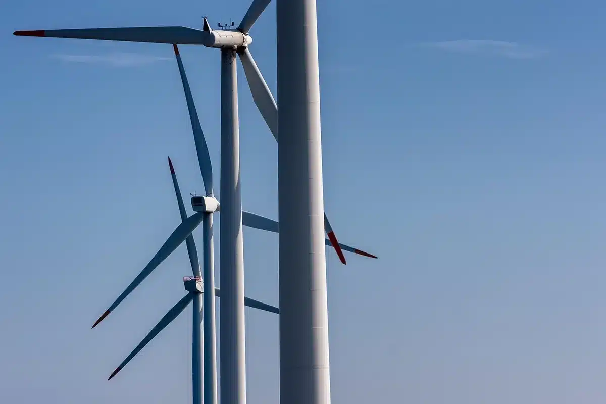 Chantier d'infrastructure éoliennes et lignes électriques sous ciel dramatique, image anonyme