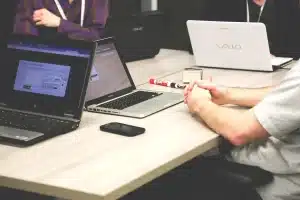 Carte de débit générique posée sur un bureau avec un ordinateur affichant une application d'investissement floue