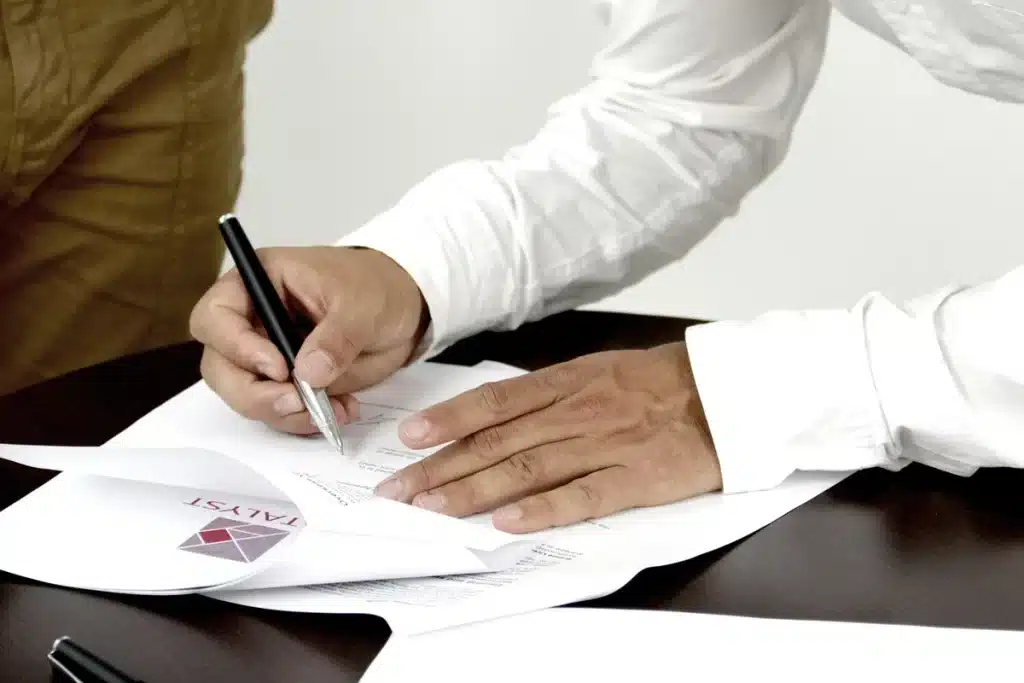 Table de réunion en journée avec dossiers et mains feuilletant des contrats