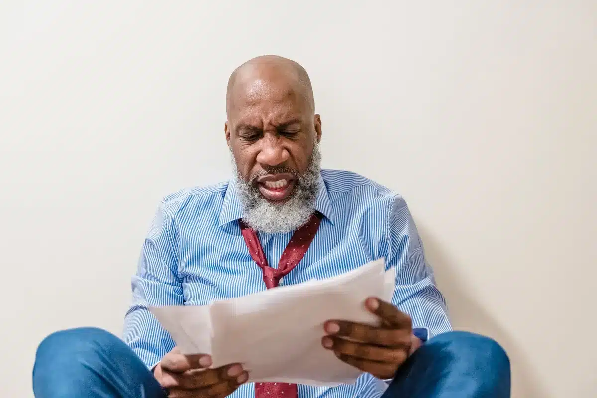 Personne examinant des papiers financiers avec une expression de doute