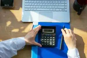 Bureau en journée, mains sur une feuille d'allocation et une calculatrice