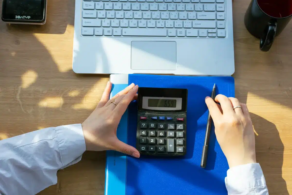 Bureau en journée, mains sur une feuille d'allocation et une calculatrice