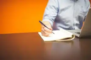 Bureau lumineux avec carnet, stylos et deux mains échangeant des notes