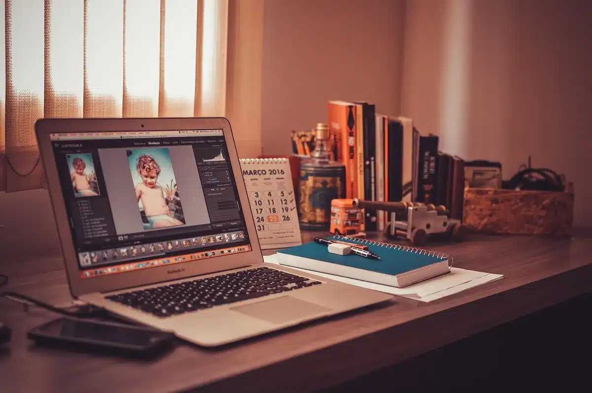 Bureau lumineux avec ordinateur portable affichant du code et carnet de notes
