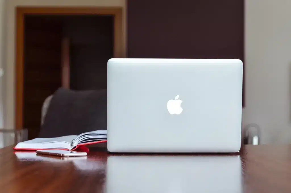 Bureau à domicile en journée avec ordinateur montrant graphiques de trading et carnet