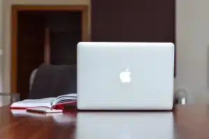 Bureau à domicile en journée avec ordinateur montrant graphiques de trading et carnet