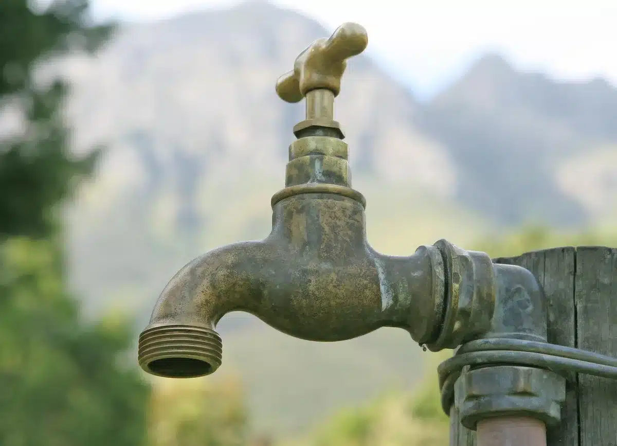 Main anonyme coupant une vanne d'arrivée d'eau dans une cuisine en plein jour