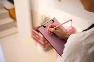 Bureau lumineux avec ordinateur portable, carnet et mains anonymes en train de taper