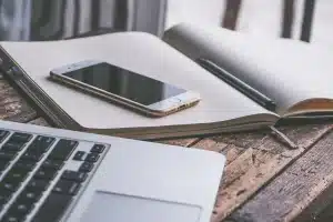Bureau lumineux avec documents de formation et ordinateur, mains anonymes préparant un dossier