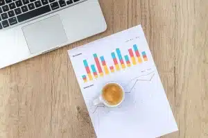 Table de réunion en journée avec documents, ordinateur et mains anonymes pointant un graphique